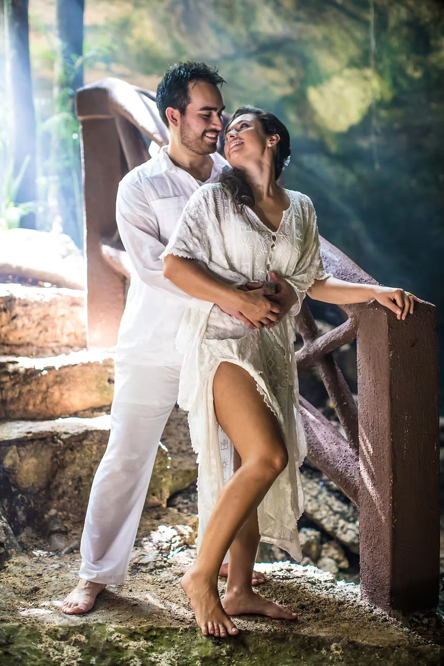 Couple in white embracing in a sunlit cenote cave during a trash-the-dress session — destination wedding photography by Murrieta Media